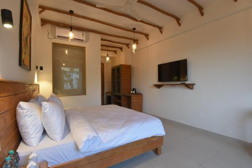 a bedroom with a bed with white sheets and a television at Ekawa Ganga by Lawrence Hotels in Rishīkesh