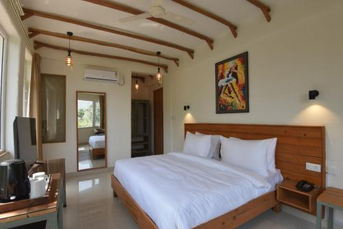 a bedroom with a large bed and a television at Ekawa Ganga by Lawrence Hotels in Rishīkesh