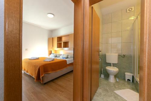 a bedroom with a bed and a bathroom with a toilet at Apartments Marko - amazing sea view in Brela