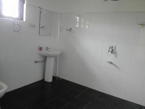 a white bathroom with a sink and a toilet at Sigiriya Peacock Homestay in Sigiriya