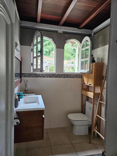 a bathroom with a sink and a toilet and two windows at Villa les Bougainvilliers in Rivière-Pilote