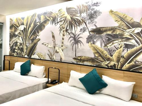 two beds in a room with a mural of palm trees at Milash Boutique Hotel in Ha Long