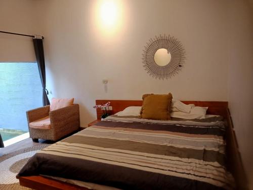 1 dormitorio con cama, espejo y silla en Punyan Poh Villas, en Denpasar