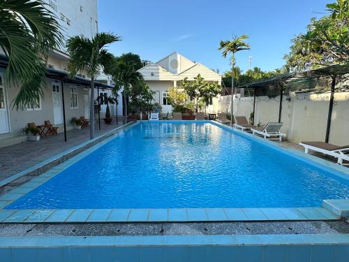 a large blue swimming pool in front of a house at Pharos Guesthouse in Mui Ne