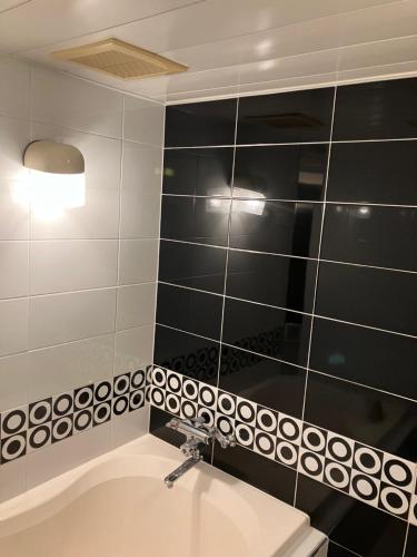 a bathroom with a sink and a black and white tiled wall at Hotel Angel (Adult Only) in Yokohama