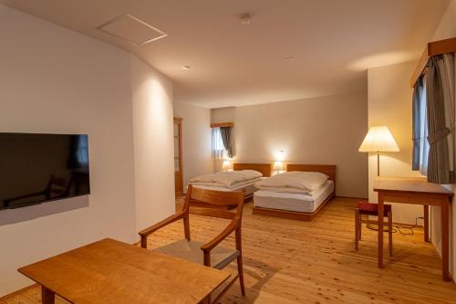 a hotel room with two beds and a table at Hotel Haus St Anton in Nozawa Onsen