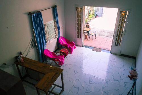 a room with pink chairs and a woman sitting at a table at Jungle House Kep 2 in Phumĭ Ŏng Char