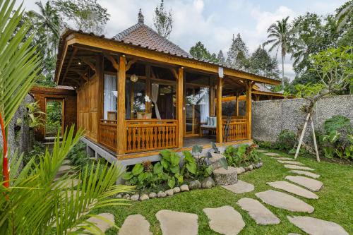 uma casa de madeira com um pátio num jardim em Anandari Ubud Villa em Ubud