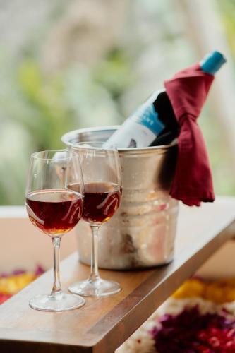 two glasses of wine sitting on a table with a bucket at Anandari Ubud Villa in Ubud