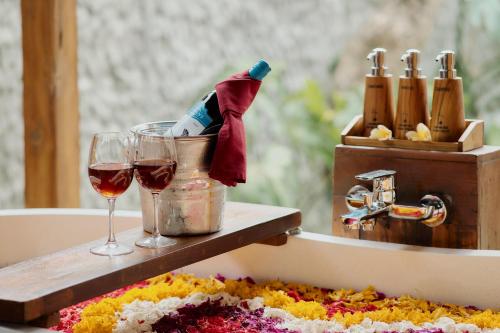 a bath tub with a bottle of wine and a glass at Anandari Ubud Villa in Ubud