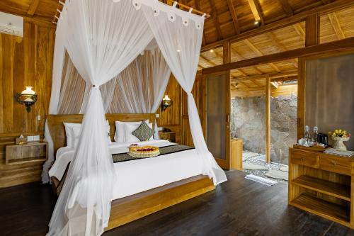 a bedroom with a bed with a mosquito net at Anandari Ubud Villa in Ubud
