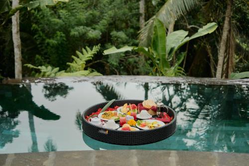 a tray of food on a table next to a pool at Anandari Ubud Villa in Ubud