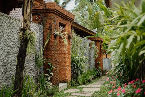 a brick walkway in front of a building with plants at Anandari Ubud Villa in Ubud