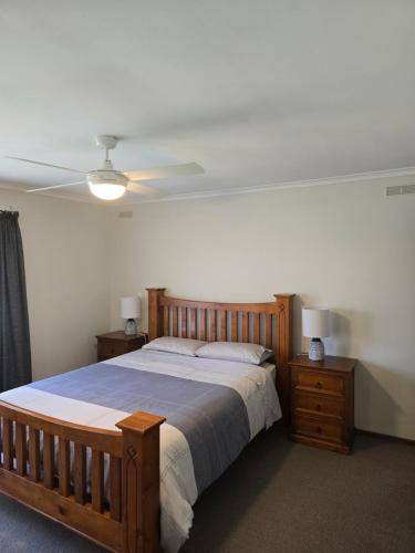 a bedroom with a wooden bed and a ceiling fan at The Golf Getaway in Myrtleford
