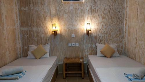 two beds in a room with lights on the wall at Salabose Cottages in Gili Air