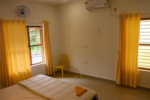 a bedroom with a bed and a window with yellow curtains at Nest Villa in Athirappilly