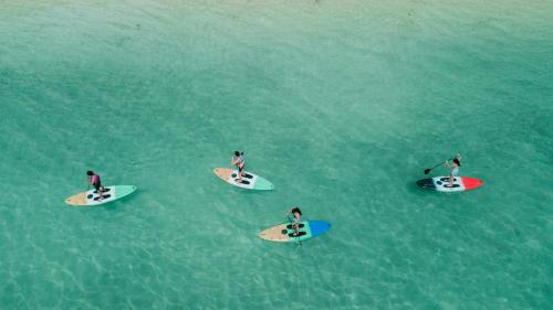 eine Gruppe von Menschen auf Surfbrettern im Wasser in der Unterkunft Durhan White Beach Resort in Tabuelan