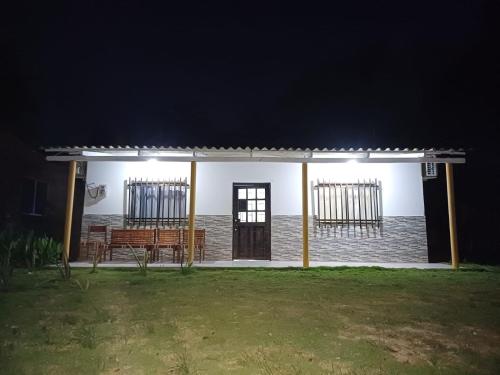 ein weißes Haus mit einer Bank in einem Hof in der Nacht in der Unterkunft Cabaña Moñitos cerca al mar e Isla Fuerte in Moñitos