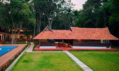uma casa com um telhado vermelho e uma piscina em Shantitheeram Ayurveda Lakeside Heritage Resort em Alappuzha