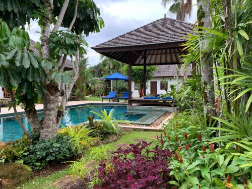 a swimming pool in a garden with a gazebo at Baan Pinya Balinese Style Pool Villa in Krabi town
