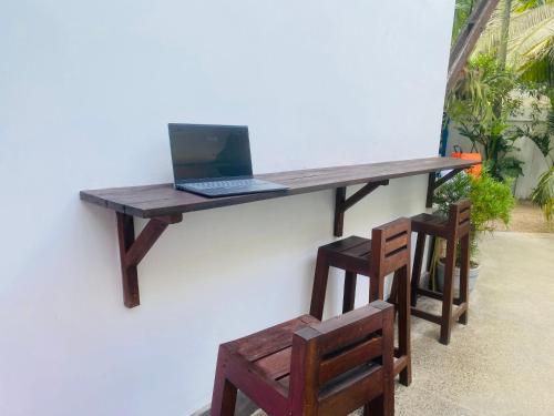 einen Schreibtisch mit einem Laptop an der Wand mit 2 Stühlen in der Unterkunft Bienvenido Cozy Marker in Matara