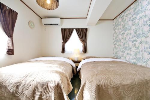 dwa łóżka w pokoju z oknem w obiekcie リーフハウス　A棟 w mieście Miyako-jima