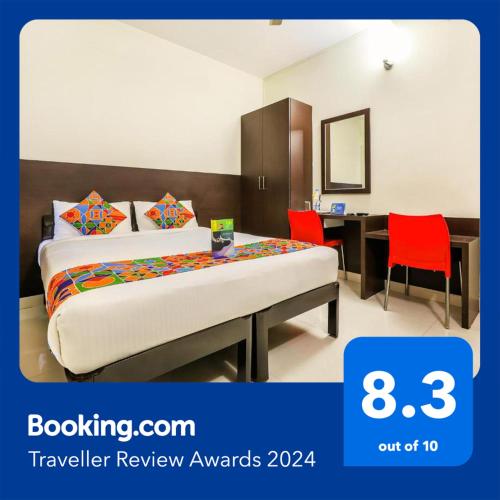 a bedroom with a bed and a desk with red chairs at FabHotel RMS Comforts - Nr Yeshwantpur Railway Station in Bengaluru