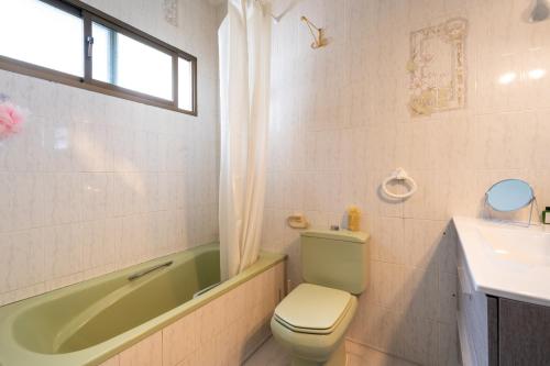 La salle de bains est pourvue d'une baignoire verte, de toilettes et d'un lavabo. dans l'établissement Family villa with garden next to the beach, à Mijas