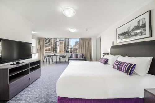 a hotel room with a large bed and a flat screen tv at Oaks Sydney Hyde Park Suites in Sydney