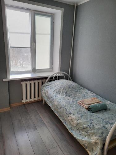 um pequeno quarto com uma cama e uma janela em Квартира em Balkhash