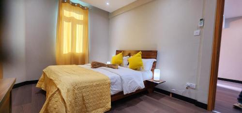 a bedroom with a bed with yellow pillows and a window at Phoenix Beach Apartments sea view in Flic-en-Flac
