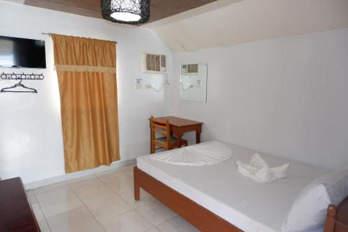 a bedroom with a bed and a table and a window at Buena Lynne's Resort in Balatero