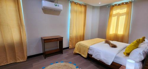 a bedroom with a bed and a window with yellow curtains at Phoenix Beach Apartments sea view in Flic-en-Flac