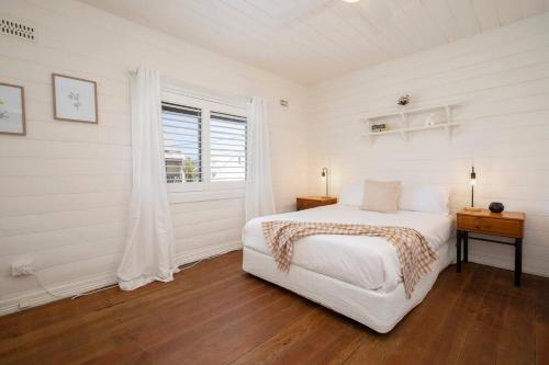 a white bedroom with a bed and a window at 'Sweet Caroline' A Classic Newcastle Hideaway in Newcastle