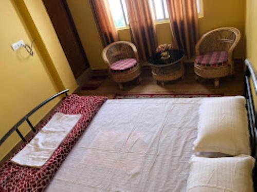 Ce lit se trouve dans un dortoir doté de chaises et d'un couvre-lit. dans l'établissement Laskus , Darjeeling, à Darjeeling