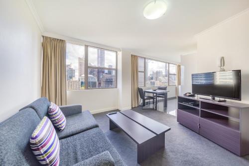 a living room with a couch and a flat screen tv at Oaks Sydney Hyde Park Suites in Sydney