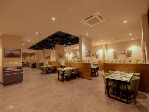 a restaurant with tables and chairs in a room at Luxo Kochi in Ernakulam