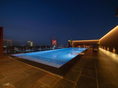 埃爾納古勒姆的住宿－Luxo Kochi，一座游泳池,在晚上在一座建筑的顶部