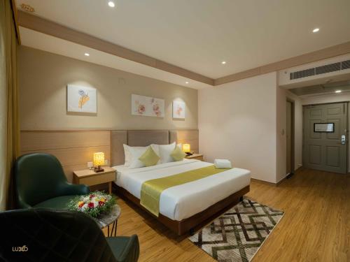 a hotel room with a bed and a chair at Luxo Kochi in Ernakulam