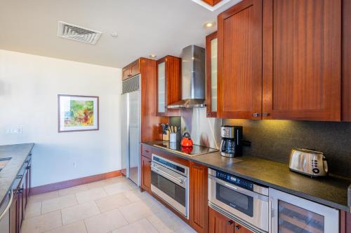 a kitchen with wooden cabinets and stainless steel appliances at Ko Olina Beach Villas O704 in Kapolei