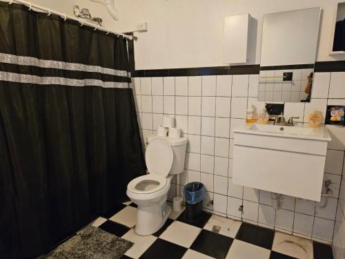 a bathroom with a toilet and a black shower curtain at Newly remodeled 2nd Floor Unit, 5 BR in Mayaguez