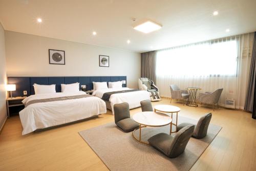 a hotel room with two beds and a table and chairs at Gangjin K-Stay Tourist Hotel in Gangjin