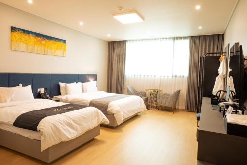 a hotel room with two beds and a television at Gangjin K-Stay Tourist Hotel in Gangjin