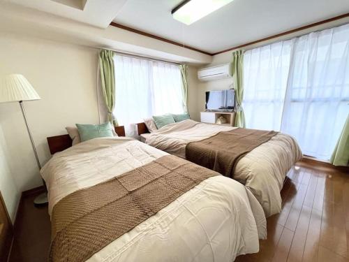 2 camas en una habitación de hotel con ventanas en Nature Flower House in Ohyama, en Tokio