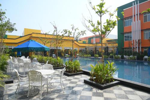 a patio with tables and chairs next to a swimming pool at Mayfair World Cup Village in Rourkela