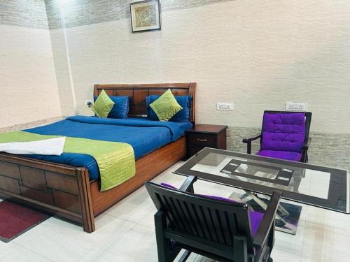 a bedroom with a bed and a table and a chair at Hotel Gangotri in Haridwār