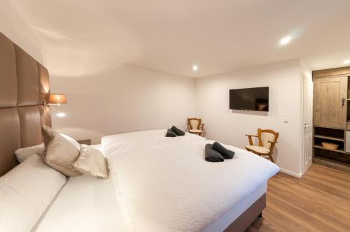a bedroom with a white bed and a flat screen tv at Landgasthaus Krimpenfort in Lohne