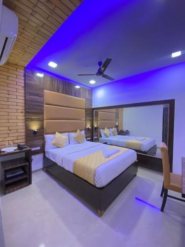 Hotel Blue Wellington - Near Mumbai Airport في مومباي: سريرين في غرفة نوم مع إضاءة أرجوانية