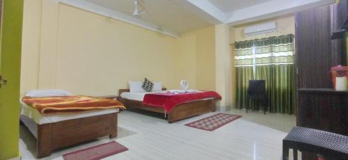 1 dormitorio con 2 camas y ventana. en Hotel Kaziranga Holidays, en Kāziranga
