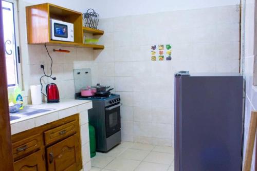 a small kitchen with a stove and a refrigerator at Résidence OSTHOME in Douala